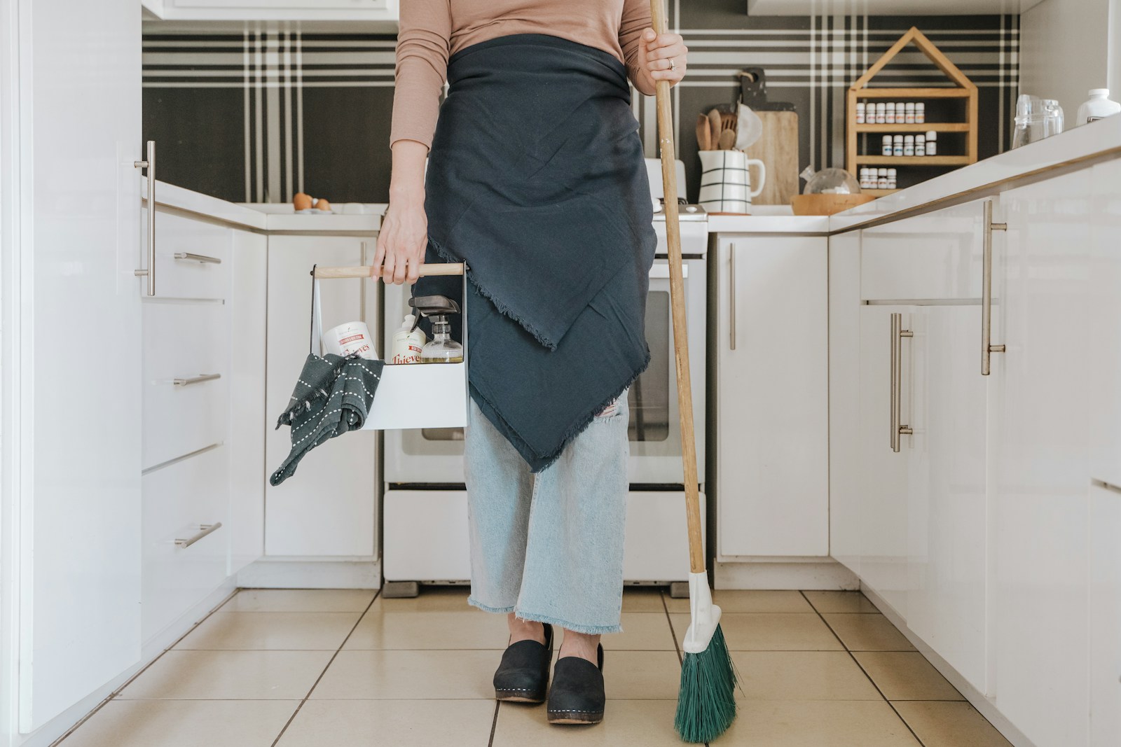 une femme debout dans une cuisine tenant un balai